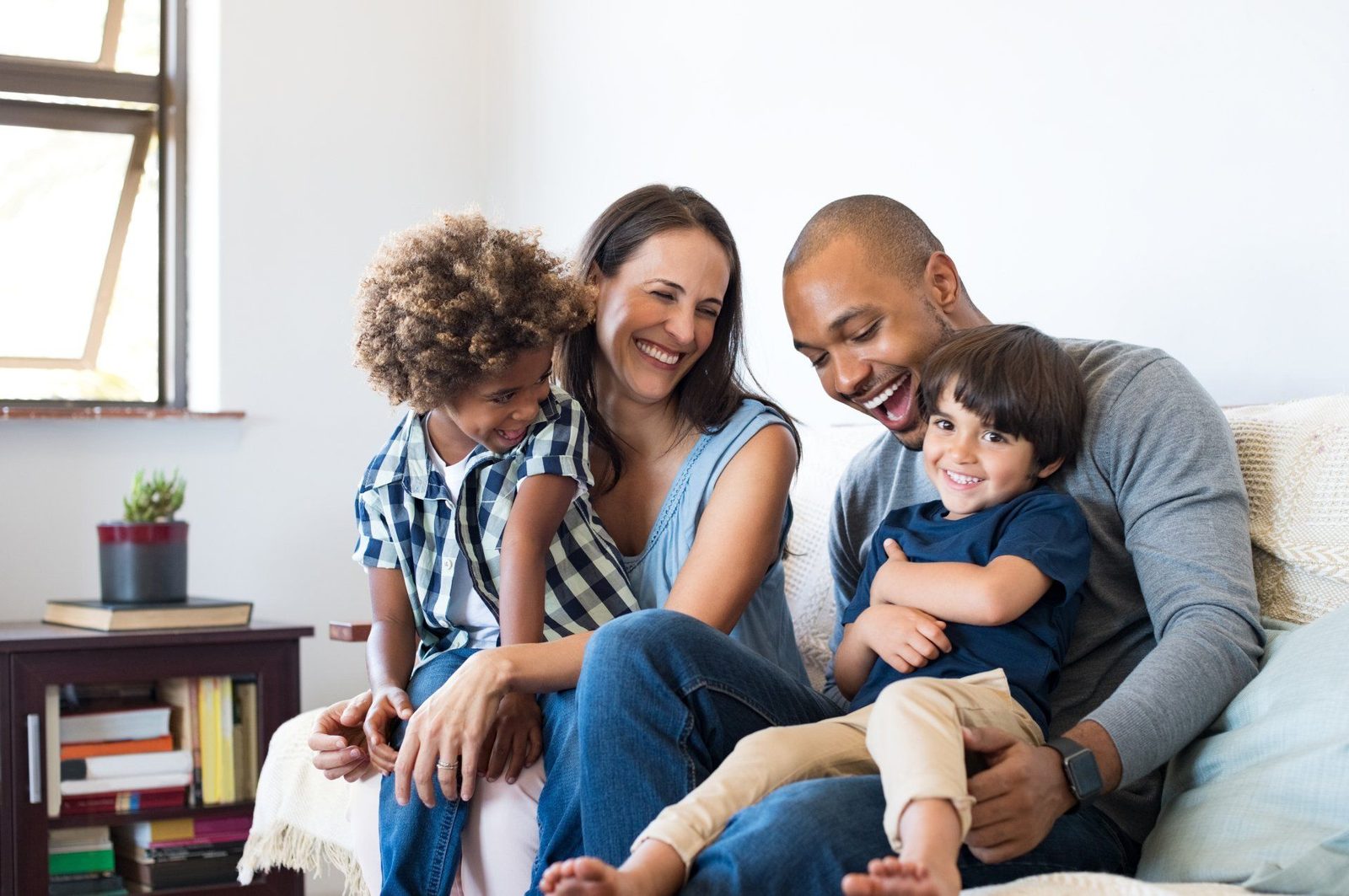 una familia está sentada junta en un sofá y sonriendo.