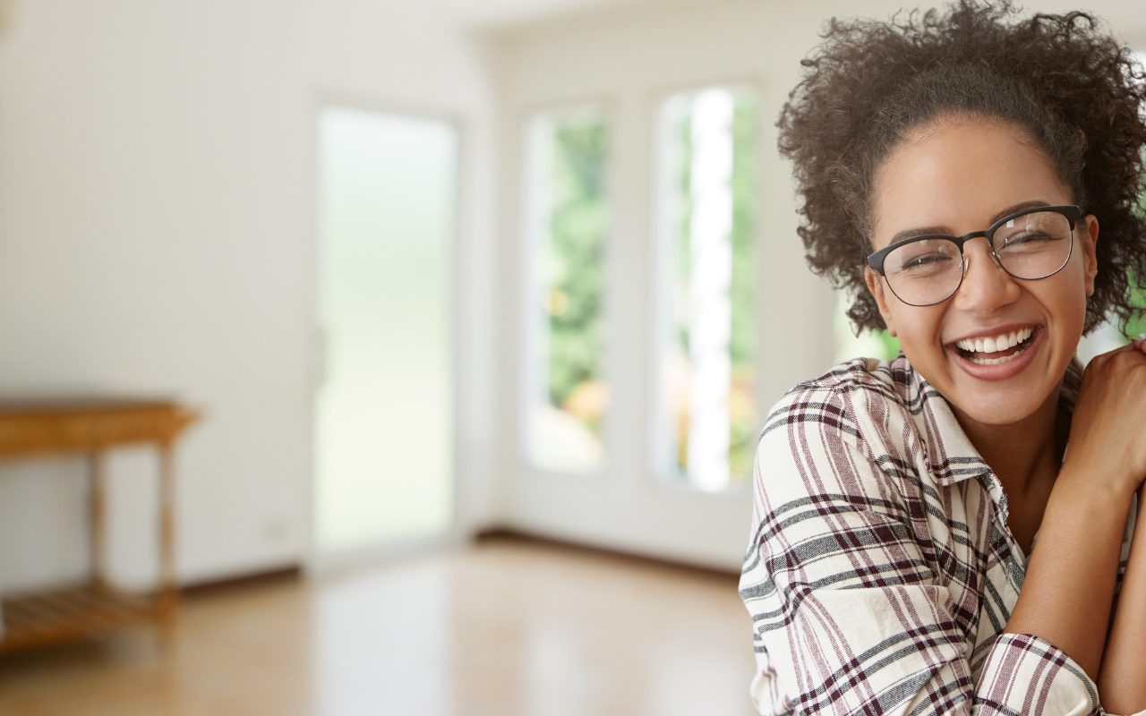a woman wearing glasses is smiling in an empty room .