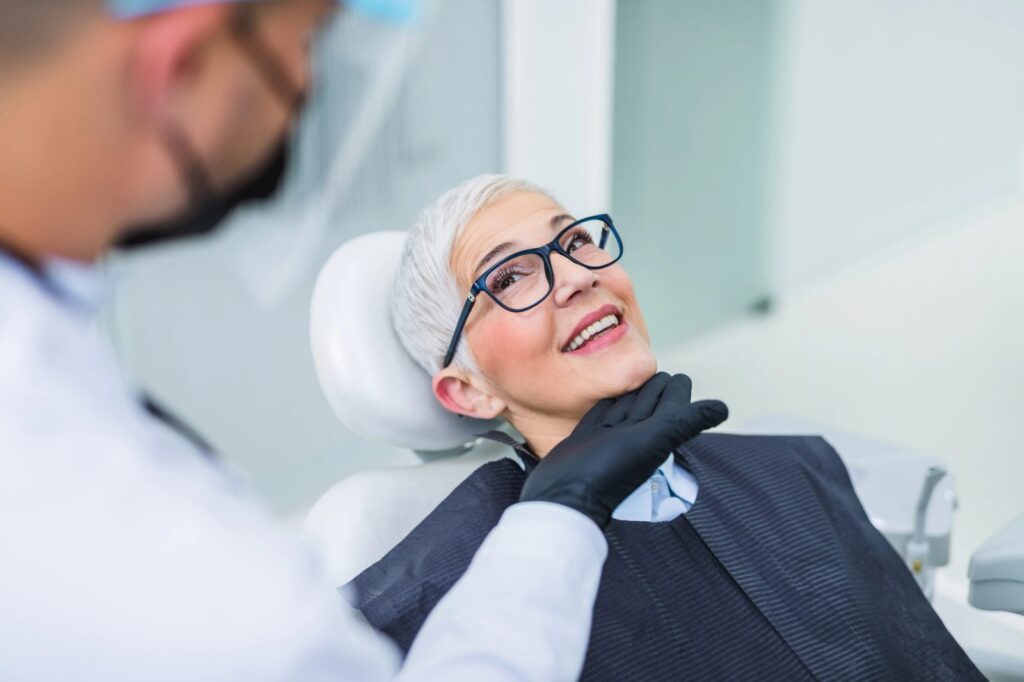 a woman is sitting in a dental chair while a dentist examines her teeth .