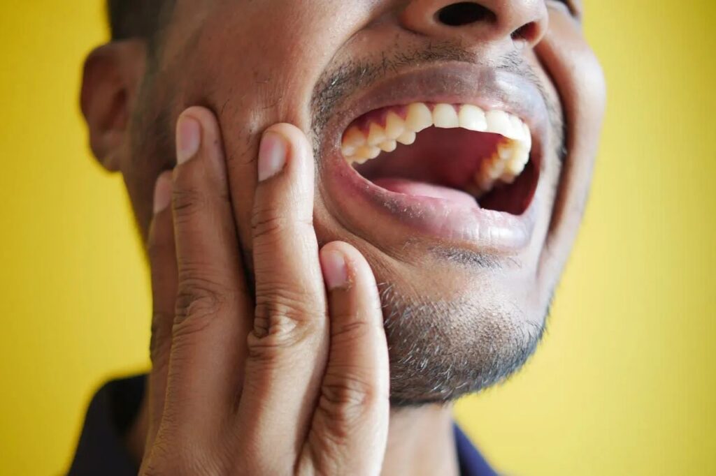 a man is holding his face in pain because he has a toothache .