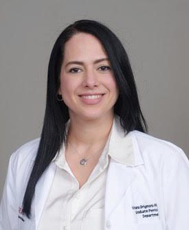 a woman in a white lab coat is smiling for the camera .